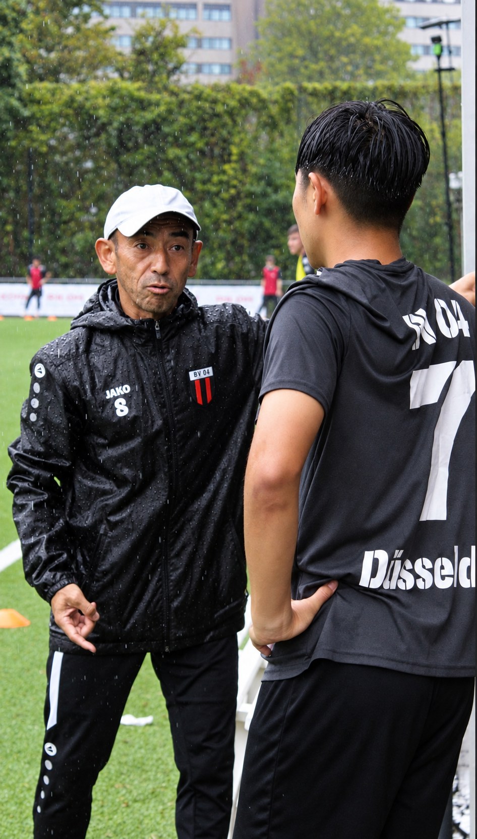 Jin im Gespräch mit einem Spieler am Spielfeldrand